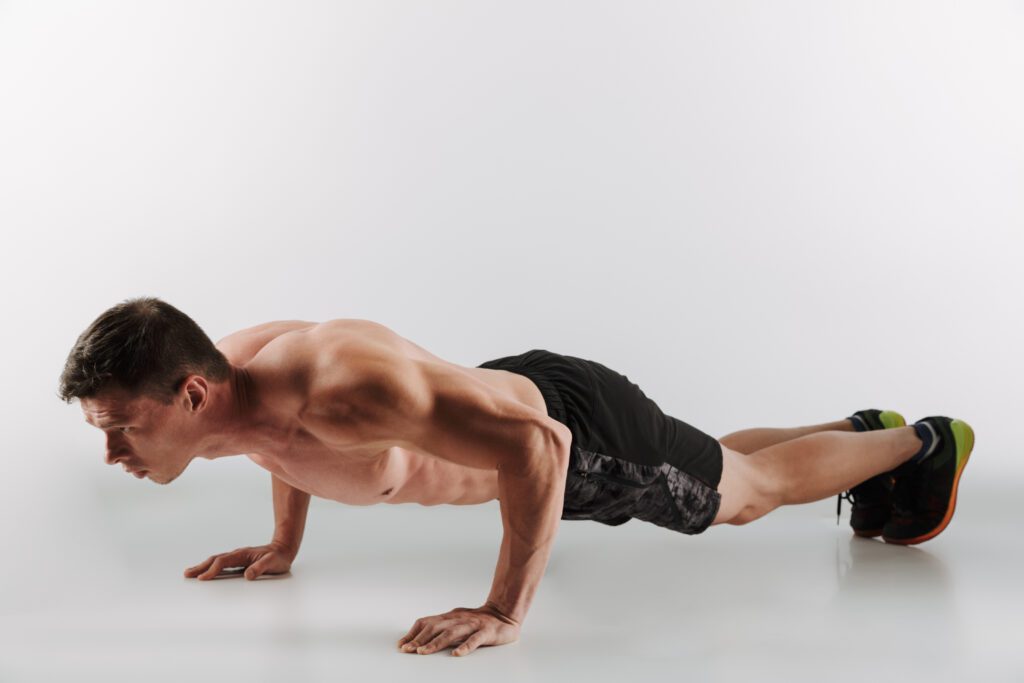 Picture of concentrated young sportsman make sport exercises isolated over grey background. Looking aside.